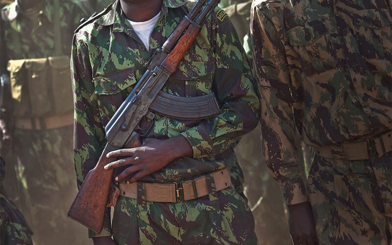 Mozambican soldier waits in line with an AK-47