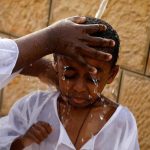 A boy is washed during a baptism ceremony