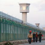 Workers walk by the perimeter fence in Dabancheng in Xinjiang Uighur Autonomous Region