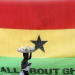 A-girl-walks-past-a-flag-of-Ghana