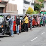 Drivers-push-their-three-wheelers-while-waiting-in-a-line-to-buy-petrol