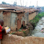 A-boy-disposes-of-raw-sewage-into-a-stream