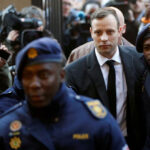 Oscar-Pistorius-is-escorted-by-police-officers