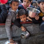 Palestinian children wait to receive food