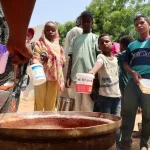 People hold pots_volunteers distribute food_Omdurman_Sudan