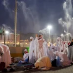 Muslim pilgrims pray as sprinklers spray water to