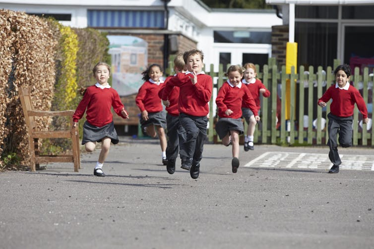 Young children run in a school playground.
